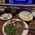 A meal consisting of a steak, green beans, and roasted potatoes, along with a side salad and a drink, is served at a table with a view of a stage displaying the title 