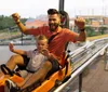 Two people are enjoying a thrilling ride on a mountain coaster laughing joyfully as they descend the track