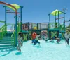 Three people are enjoying a sunny day at a water park sliding down in a large inflatable ring with big smiles on their faces