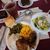 This image shows a hearty meal consisting of a dinner roll, green beans, macaroni and cheese, gravy-covered meat with mashed potatoes, a piece of fried chicken, salad on a small plate, a slice of chocolate cake, and a glass of iced tea, all arranged on a maroon-colored table.