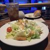 A plate of salad with a glass of iced tea is set on a table in front of a stage with blue lighting.