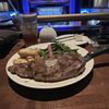 A steak dinner with a side of green beans and potatoes is served in front of a stage with the words 