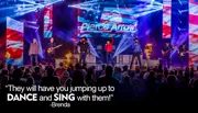 A band is performing energetically on stage with colorful lights, American flag imagery, and a cheering crowd, alongside a quote praising their ability to make the audience dance and sing.