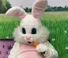 A person dressed in a large fluffy bunny costume is seated on a red childrens ride-on train in an indoor play area