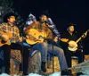 The image is a collage of four different photos themed around a traditional Western or cowboy lifestyle featuring musicians in cowboy attire a person smoking meat old-fashioned kitchen items and a plate of hearty food typically found in American Western cuisine