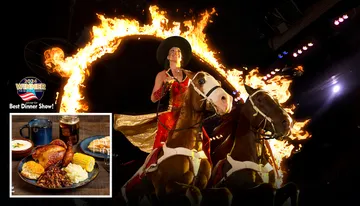 A performer rides two horses through a flaming ring in a dramatic, lit-up setting.