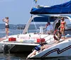 A group of people enjoys a sunny day sailing on a boat named Spirit of America with a backdrop of a lakeshore and buildings