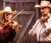 The image depicts a cheerful band of musicians dressed in Western attire playing country music juxtaposed with an inset picture of traditional Southern cuisine embodying a vibrant celebration of American Southwestern culture